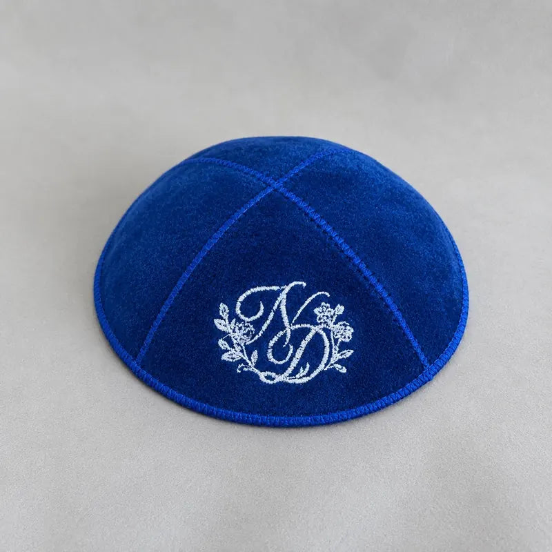 Initiales "ND" brodées en fil argenté avec fioriture florale, sur une kippa bleu roi — un rendu mariage haut de gamme.